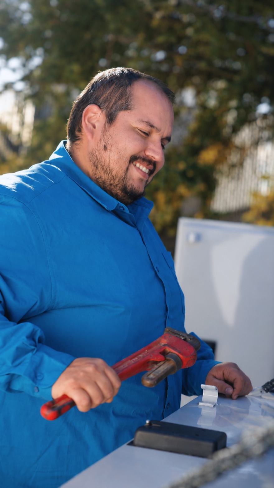 An Elite Rooter technician holding a pipe wrench at a service vehicle