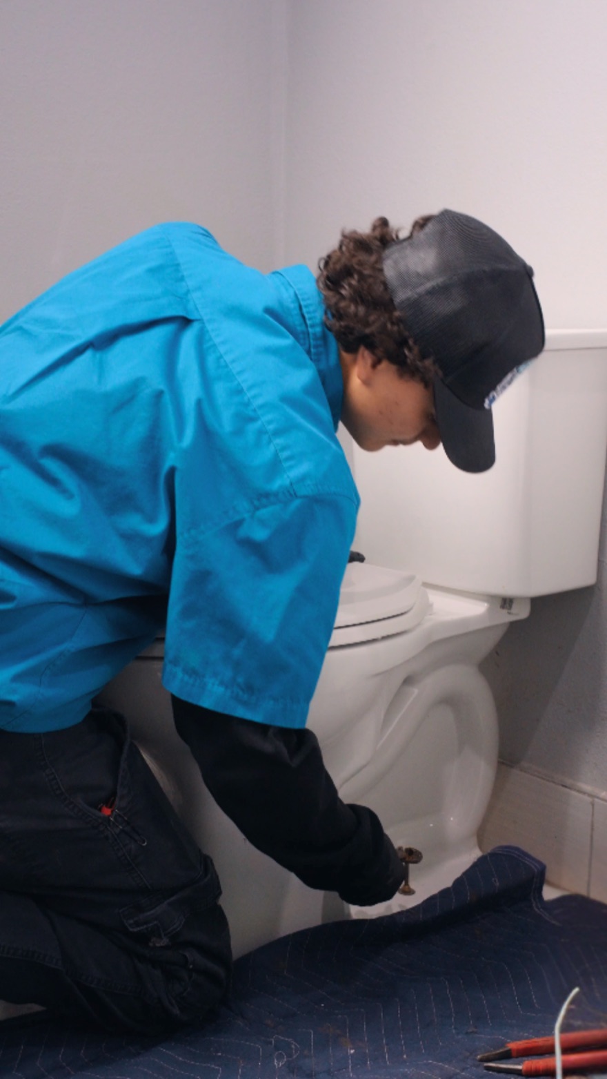 An Elite Rooter technician working beside a toilet with floor protection in place