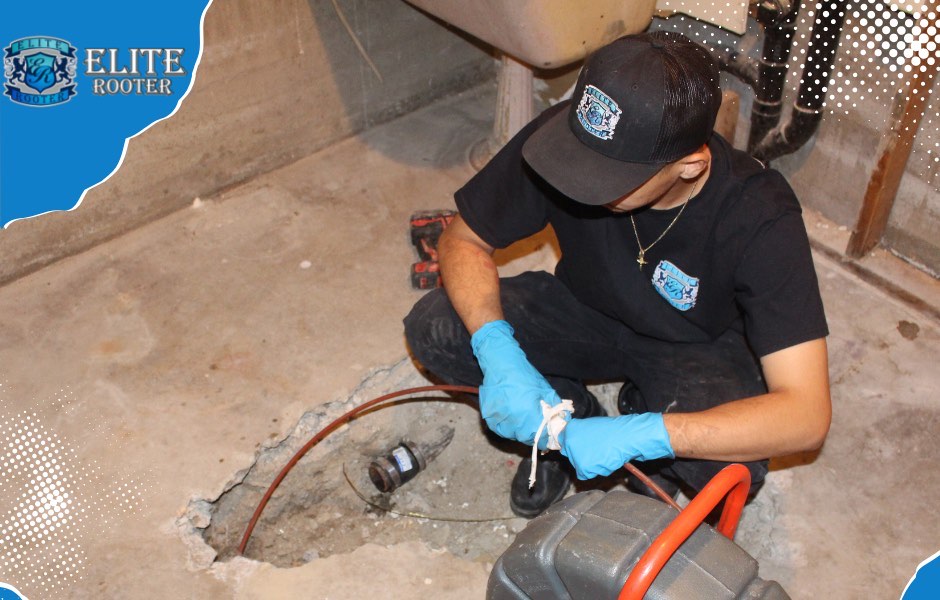 Elite Rooter technician working with drain cleaning equipment beside an exposed line