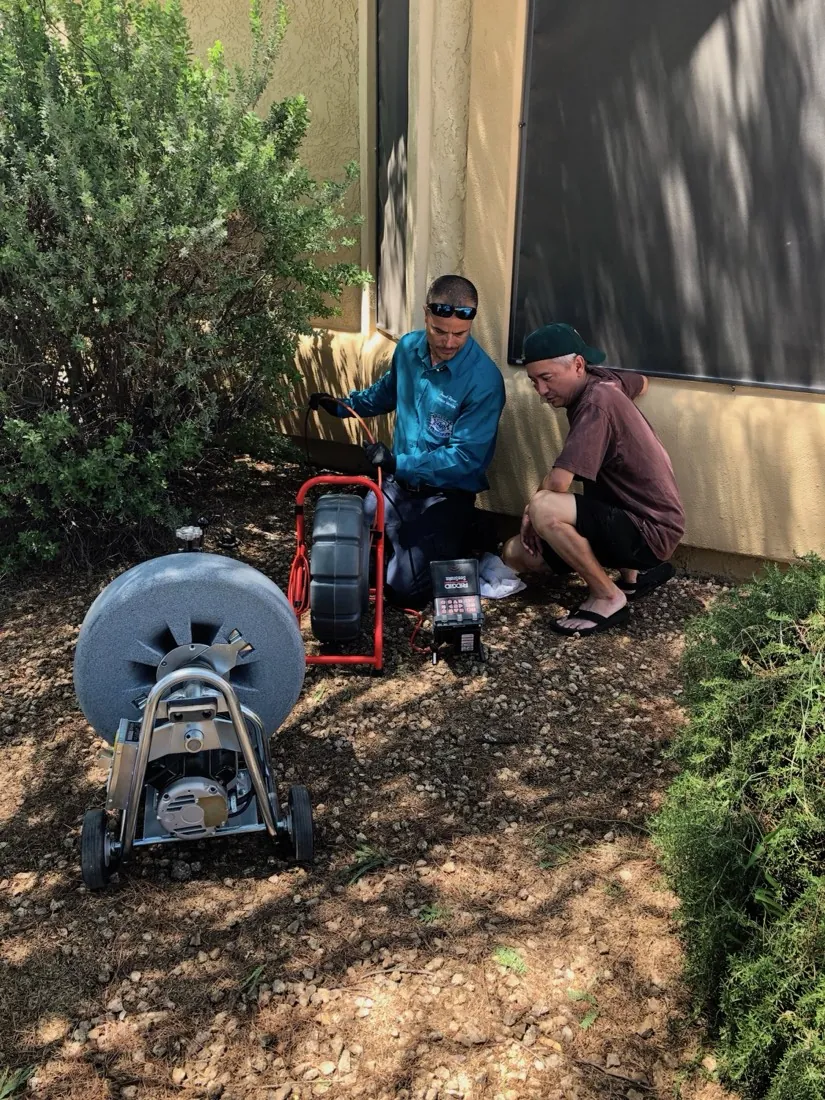 Elite Rooter technician reviewing inspection equipment with a customer