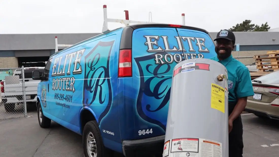An Elite Rooter technician moving a water heater beside a branded service van