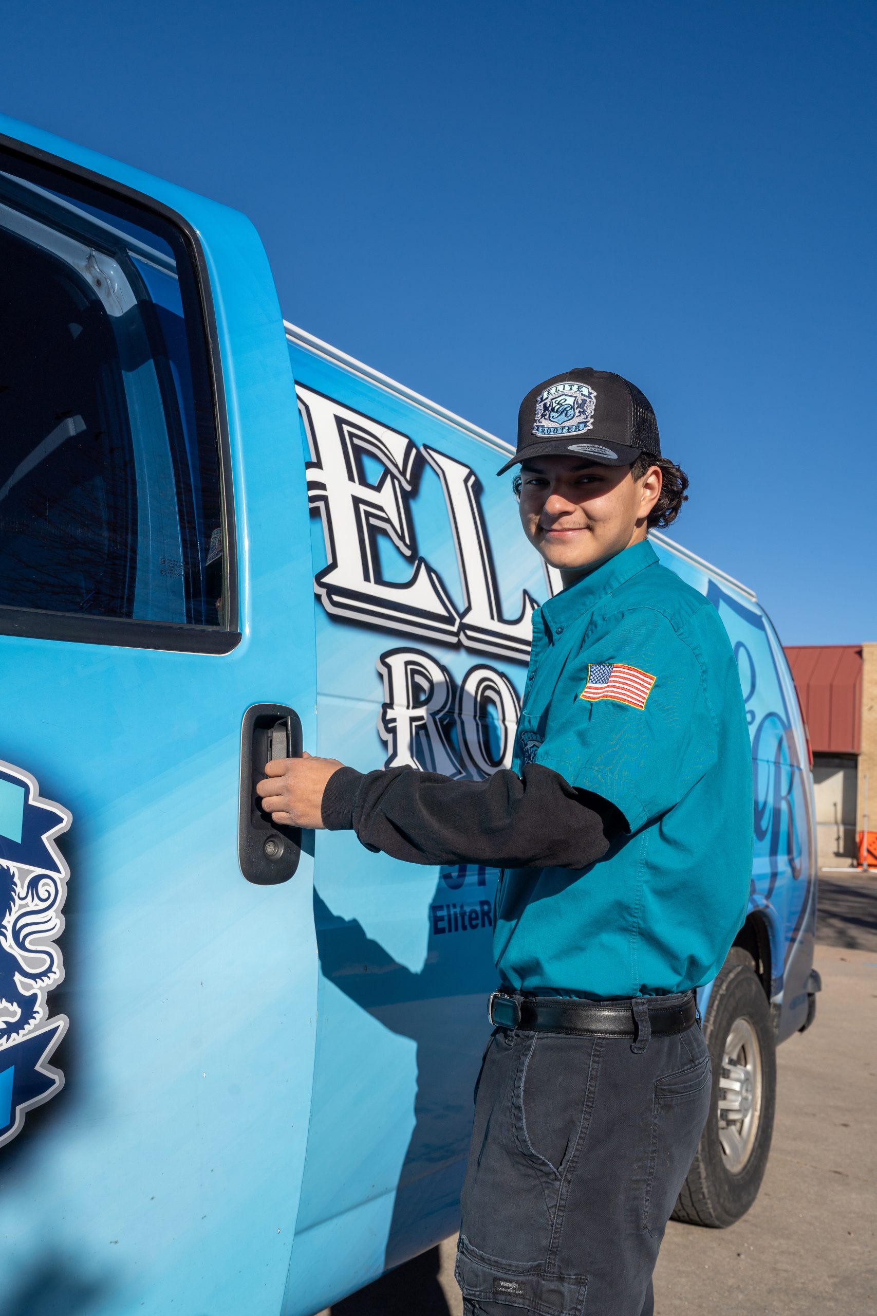 Elite Rooter local plumbing technician beside a service vehicle